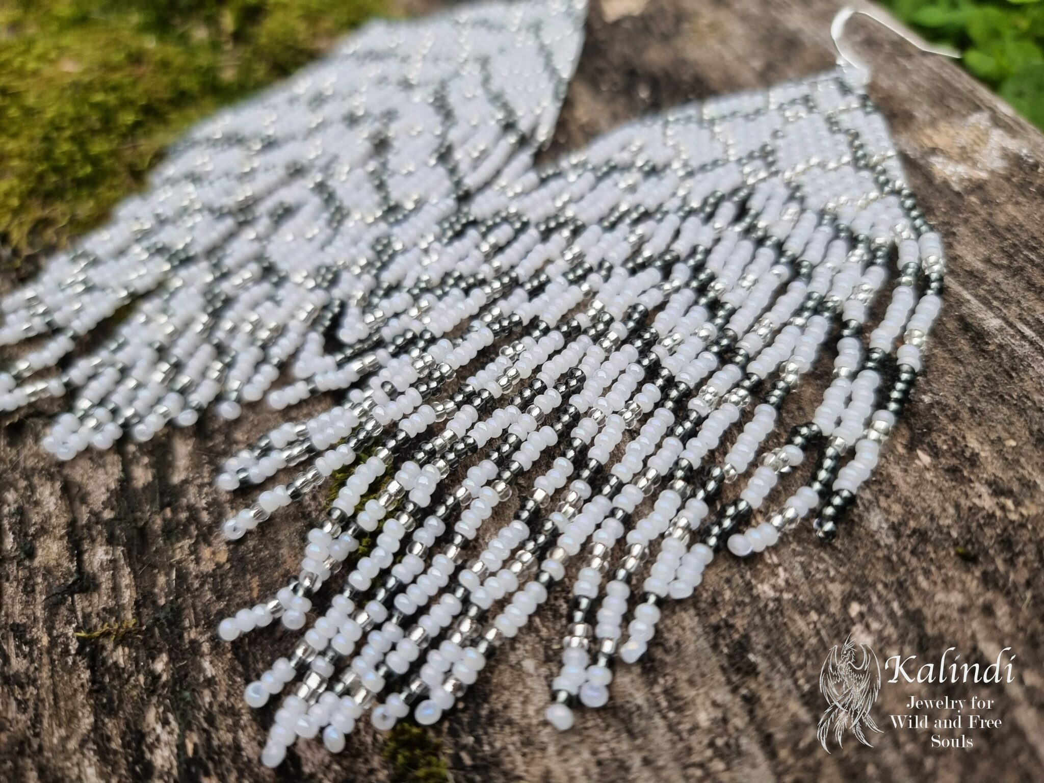 Long white beaded earrings in the shape of a feather